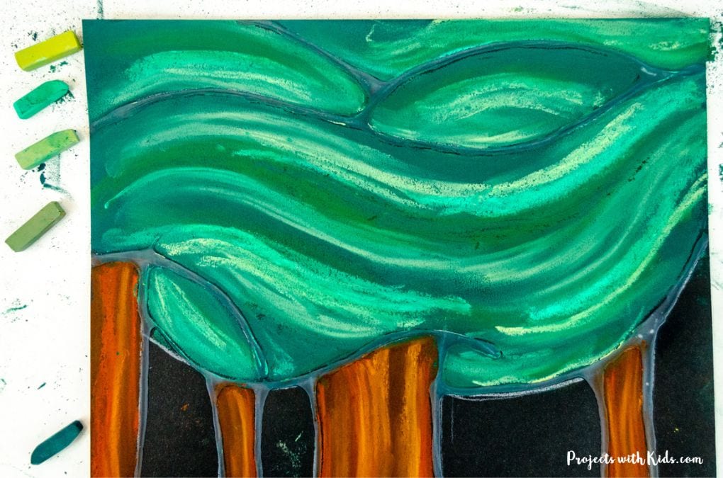 Layering different shades of green on trees with chalk pastels on black paper.